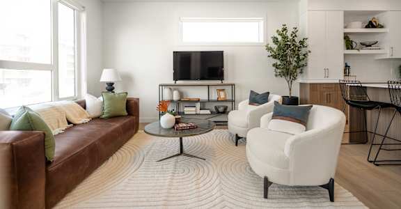 A living room with a brown couch, a white chair, and a coffee table.