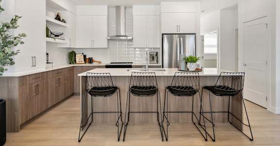 A modern kitchen with a bar area and three chairs.