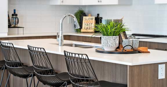 A kitchen with a white countertop and black chairs.