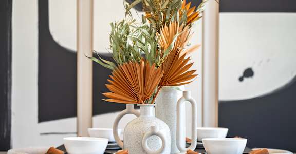 A table setting with a white vase and bowls.