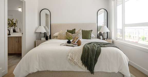 A bedroom with a large bed and two mirrors above it.