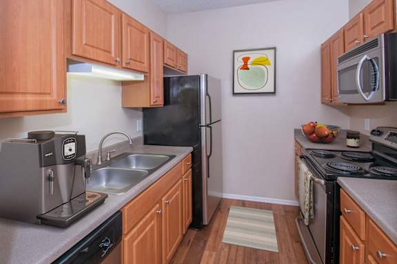 A kitchen with wooden cabinets and a black refrigerator.