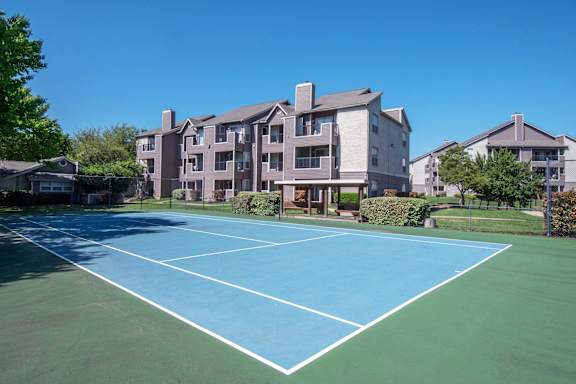 A tennis court in front of apartment buildings.
