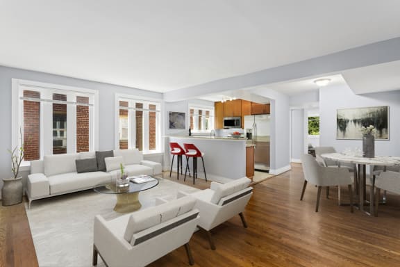 a living room with white couches and chairs and a kitchen with a breakfast bar