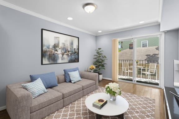 a living room with a gray couch and a white coffee table with a vase of flowers