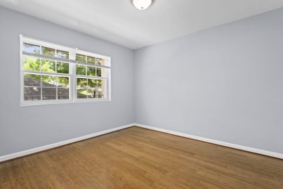 an empty room with hardwood floors and a large window