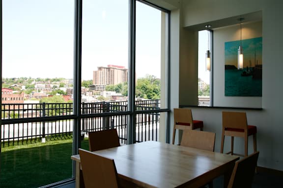 A table with chairs in front of a window with a view of a city.at 66 Main, New York, 10701