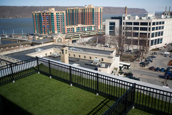 A view of a city from a balcony with a black railing.at 66 Main, New York, 10701