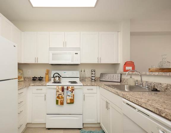 a kitchen with white cabinets and granite countertops at Promenade at the Park Apartment Homes in Seattle, WA