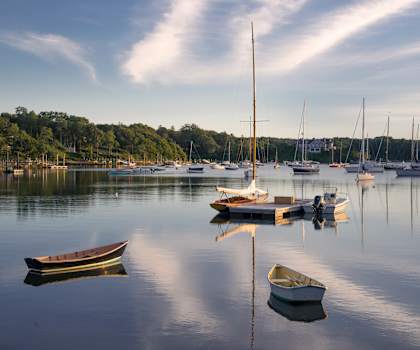 A serene lake with boats and a sailboat in the distance.