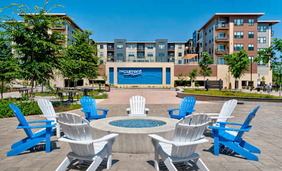 an outdoor patio with blue and white chairs and a fire pit