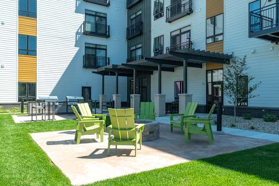 A patio with green chairs and a table in front of a building.
