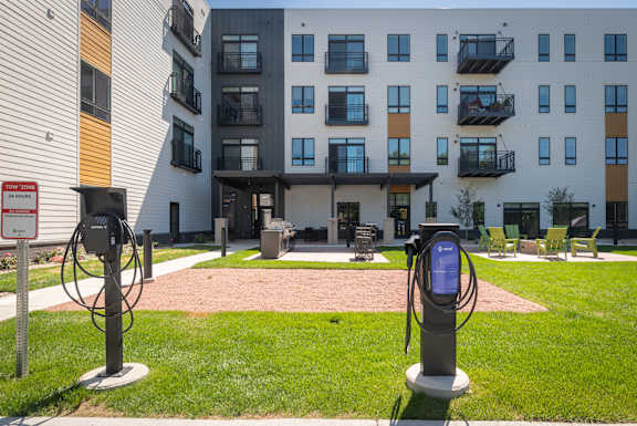 Two electric vehicle charging stations in front of apartment buildings.
