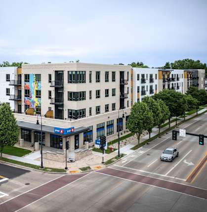 A street view of a city intersection with a white building on the corner.