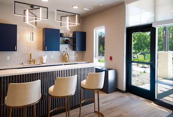 A kitchen with dark blue cabinets and white bar stools.