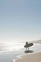 a surfer standing on the beach with a surfboard