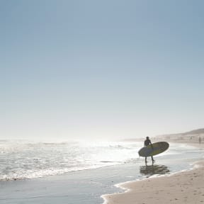a surfer standing on the beach with a surfboard
