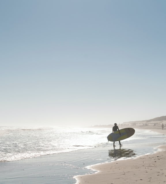 a surfer standing on the beach with a surfboard