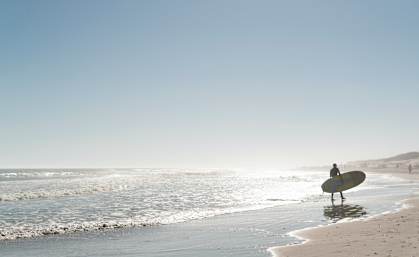 a surfer standing on the beach with a surfboard