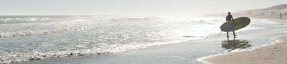 a surfer standing on the beach with a surfboard