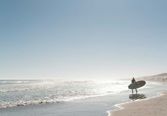 a surfer standing on the beach with a surfboard
