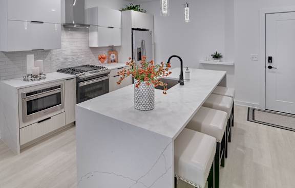 A modern kitchen with a white island and stainless steel appliances.
