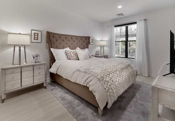 A bedroom with a large bed, a nightstand, and a window.