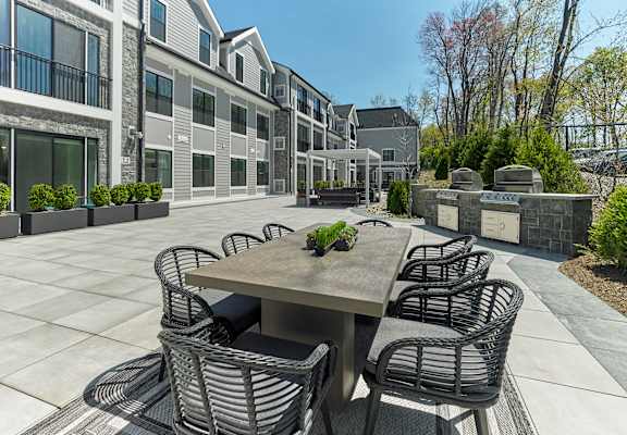 A patio with a table and chairs is surrounded by apartment buildings.