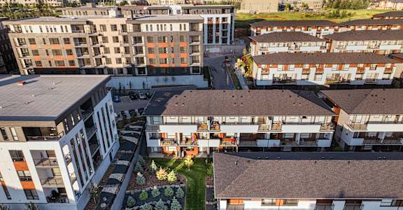 A large building with a lot of windows is surrounded by smaller buildings.