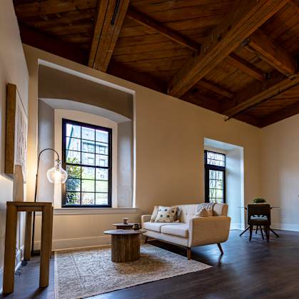 A living room with a couch, a chair, a table, and a rug. at The Dean at Creekview Apartments, Newark, Delaware