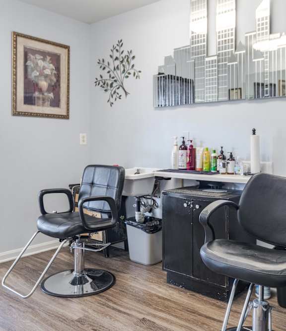 A hairdressing salon with two chairs and a mirror.