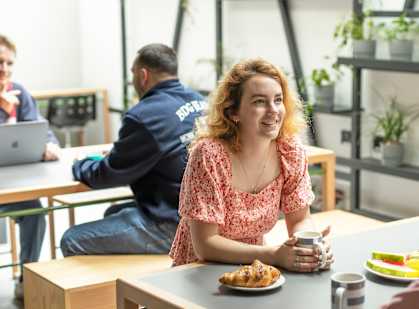 a woman sitting at a table with a cup of coffee and a plate of food