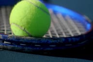 a tennis ball sitting on top of a tennis racket