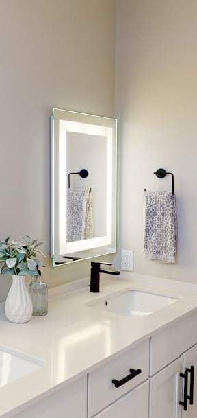 A white bathroom with a sink, mirror, and towel.