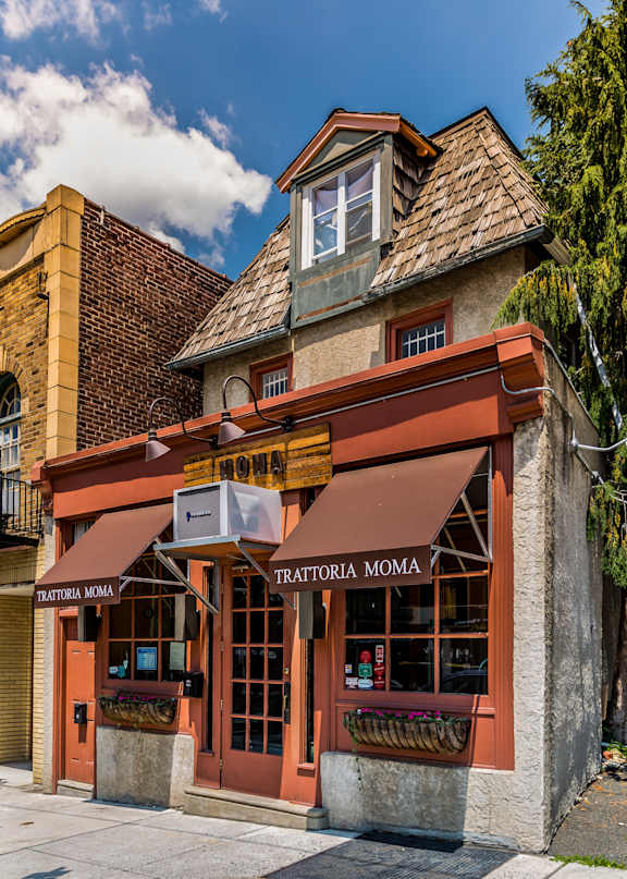 A building with a brown awning and a sign that says "Trattoria Moma".