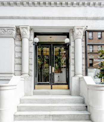 A white building with a black door and steps leading up to it.