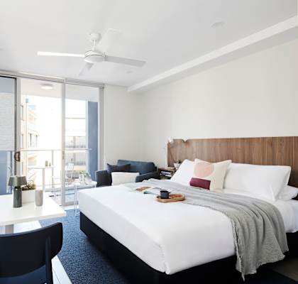 a bedroom with a bed and a desk and a balcony