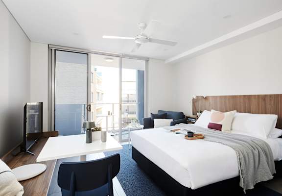 a bedroom with a bed and a desk and a balcony