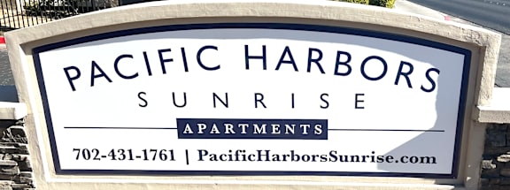 A sign for Pacific Harbors Sunrise Apartments with a phone number and website.