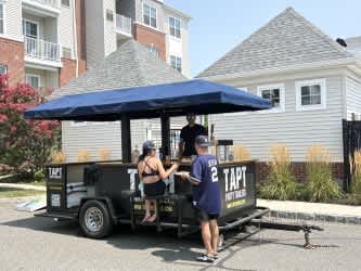 A food truck with a blue canopy is parked in front of a building.