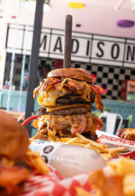 a triple decker hamburger with fries on a table