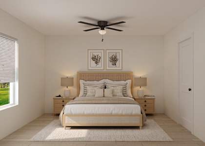 A bedroom with a large bed, two lamps, and a ceiling fan.