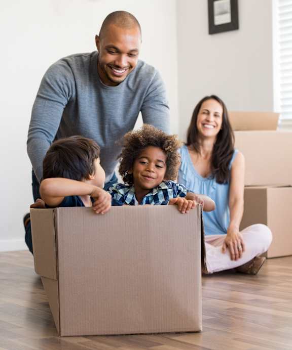 A family of four is playing in a cardboard box.