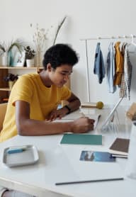 a young man sitting at a desk working on a piece of paper at Pacific Walk, Lakewood, Washington