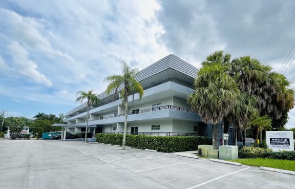 a building with palm trees in a parking lot at Lakeside @ Biscayne Gardens,North Miami, FL,33181