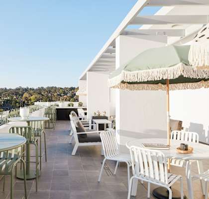 a terrace with tables and chairs and umbrellas on a roof