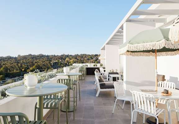 a terrace with tables and chairs and umbrellas on a roof