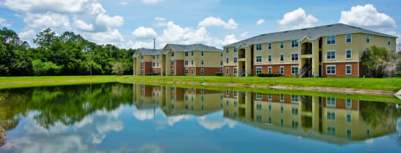 a large pond sits in front of an apartment complex