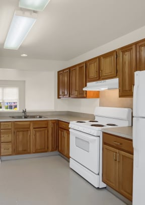 an empty kitchen with white appliances and wooden cabinets