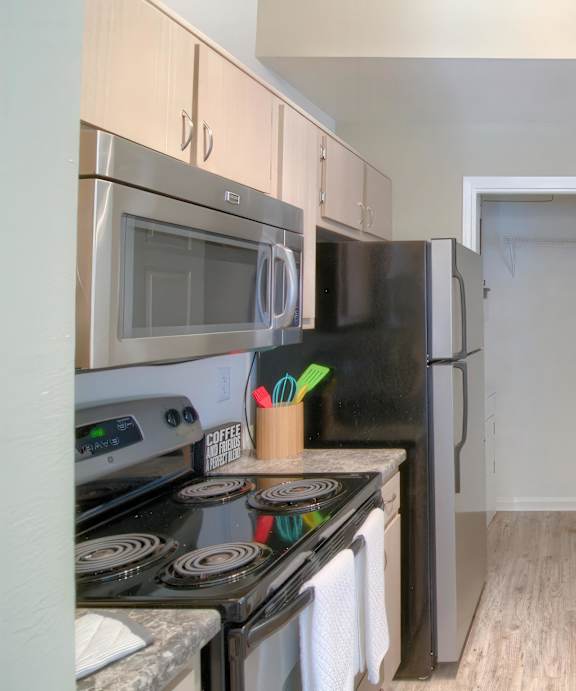 A kitchen with a stove, microwave, and refrigerator.
